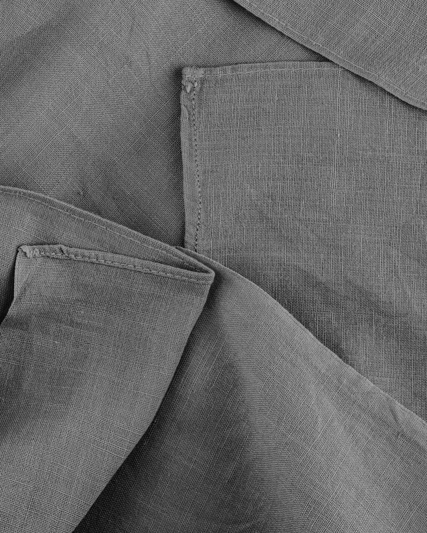 Cloth folded and overlapped, its weave and edge stitching catching the light.